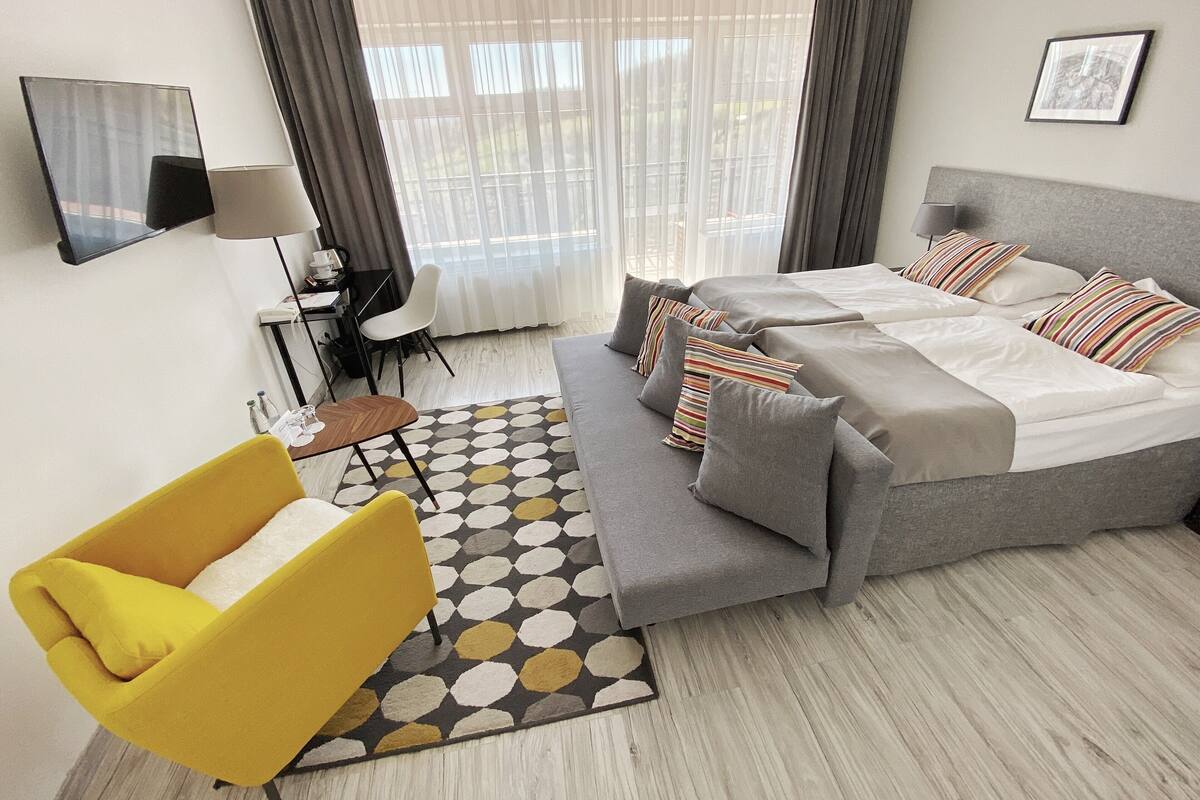Een moderne hotelkamer met een bed, een bank, een bureau en een stoel.