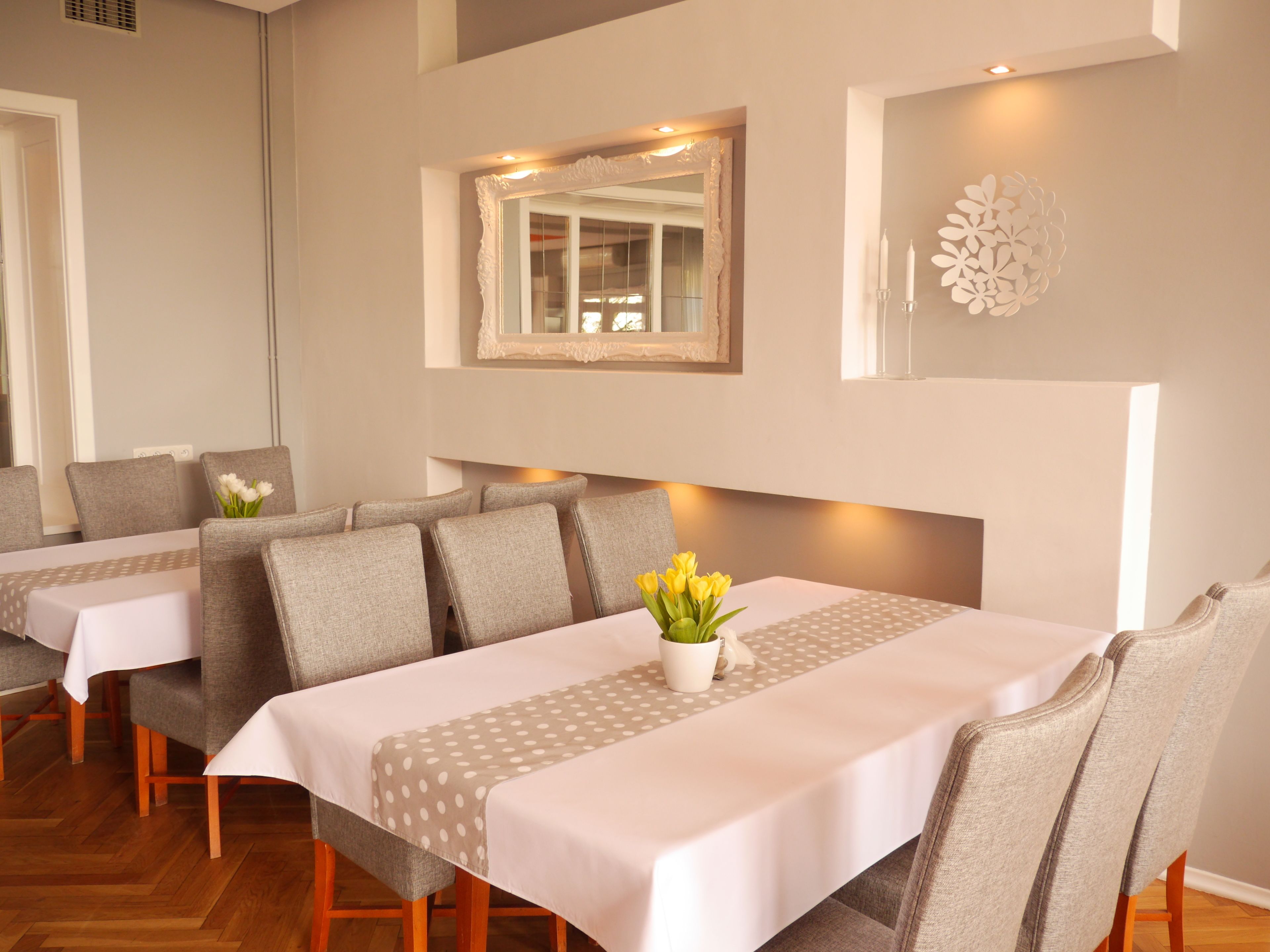 A dining area with multiple tables and chairs, a decorative mirror, and a wall-mounted light fixture.