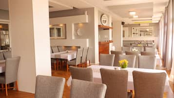 Un comedor moderno con sillas tapizadas en gris y manteles blancos.