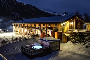 A wooden lodge with a hot tub and a wooden deck, surrounded by snow and mountains. - Agriturismo La Tresenda Mountain Farm (Livigno)