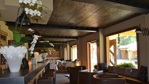 Un restaurante con una barra larga, asientos de cuero marrón y techo de madera.