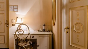 Ett hotellrum med ett skrivbord, en lampa, en flaska vin och ett bricka med glas.