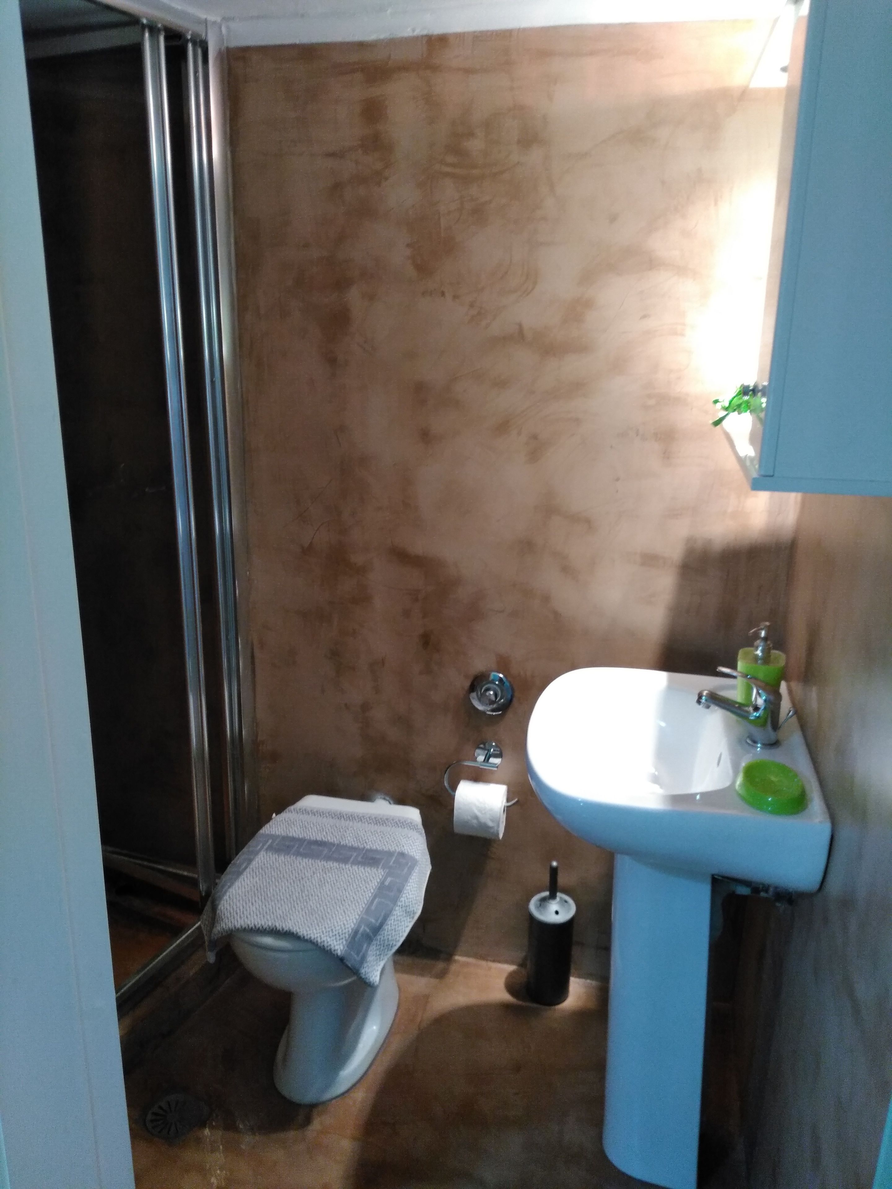 Une salle de bain avec des toilettes, un lavabo et une douche.