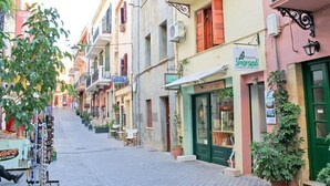 A narrow street lined with colorful buildings, including a shop with a green door and a sign for 'Smaragd'. - Smaragdi Rooms for Rent (Chania)