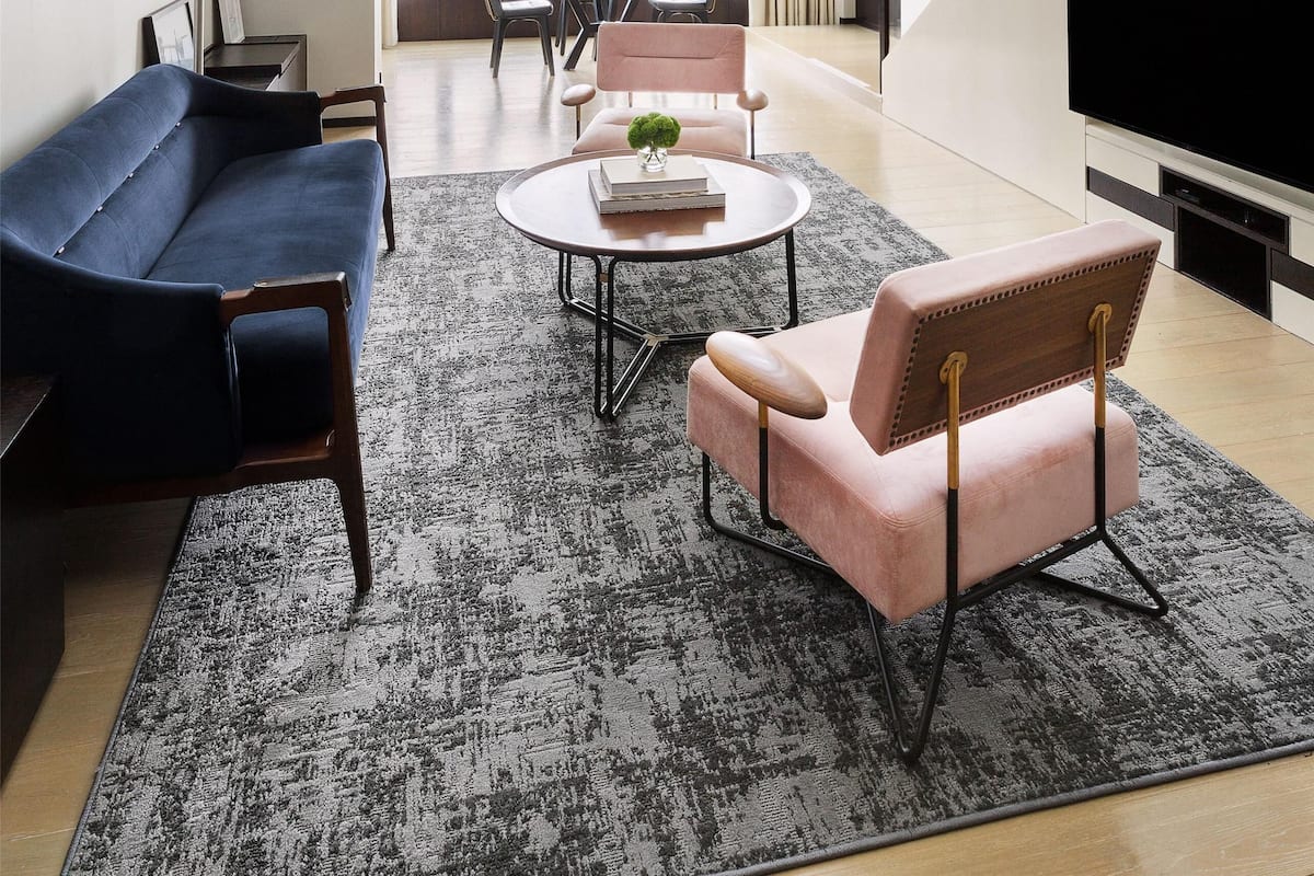 Una sala de estar moderna con sofá, sillón y mesa de centro. Una escalera conduce a un nivel superior.