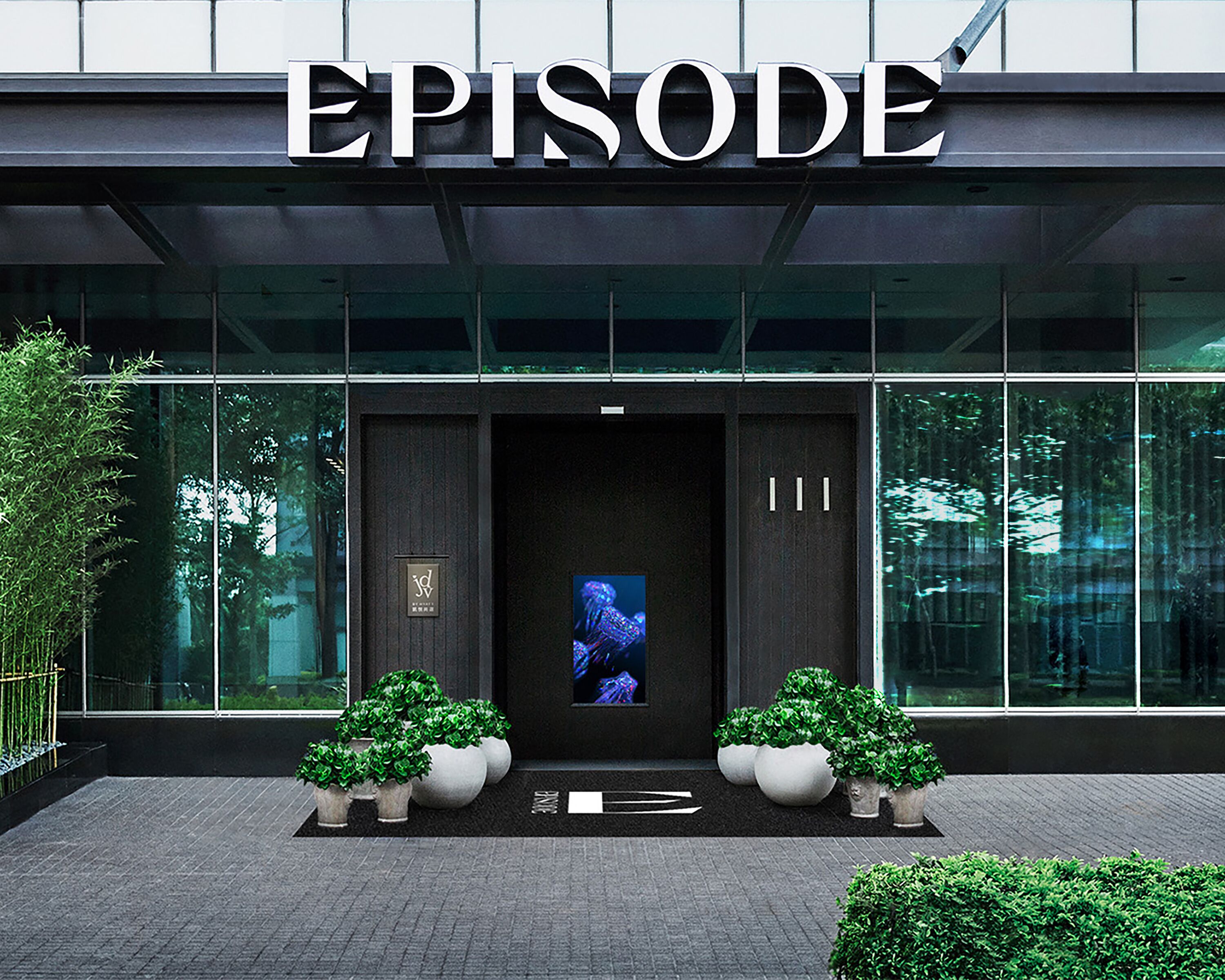 A modern building entrance with the word "EPISODE" above the door. There are two potted plants on either side of the entrance.