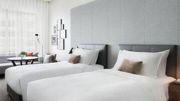 A hotel room with two beds, a sofa, a small table, and a lamp.