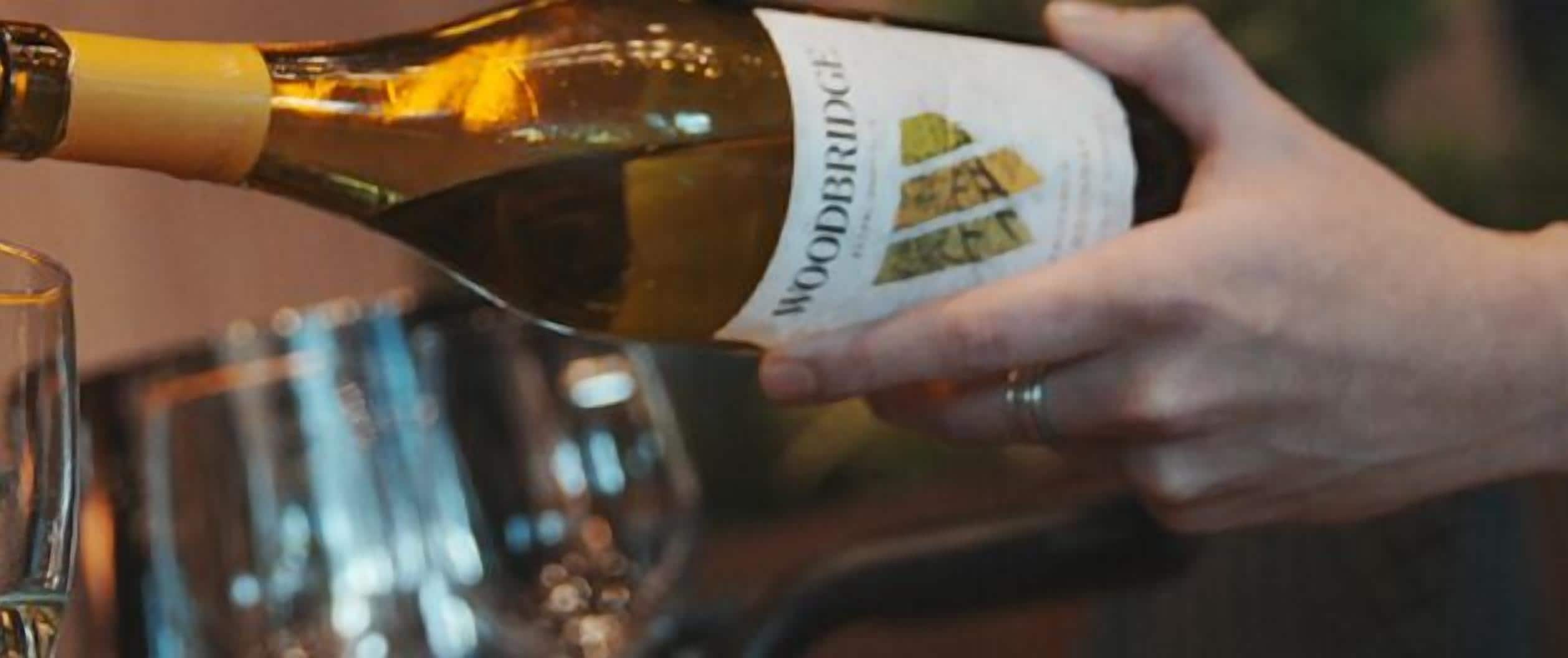 A person pouring wine from a bottle into a glass.