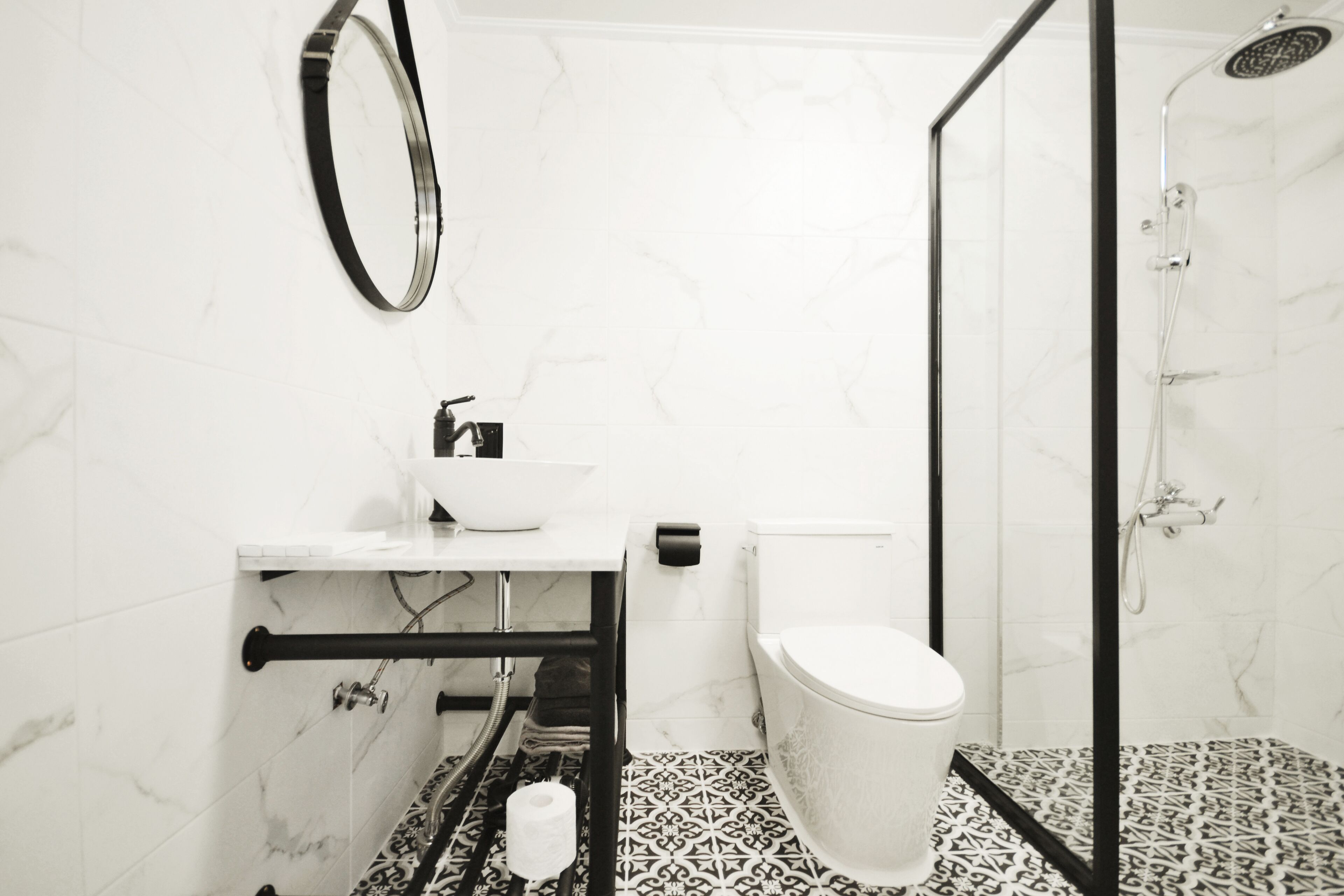 Un baño con inodoro blanco, lavamanos con espejo y zona de ducha.