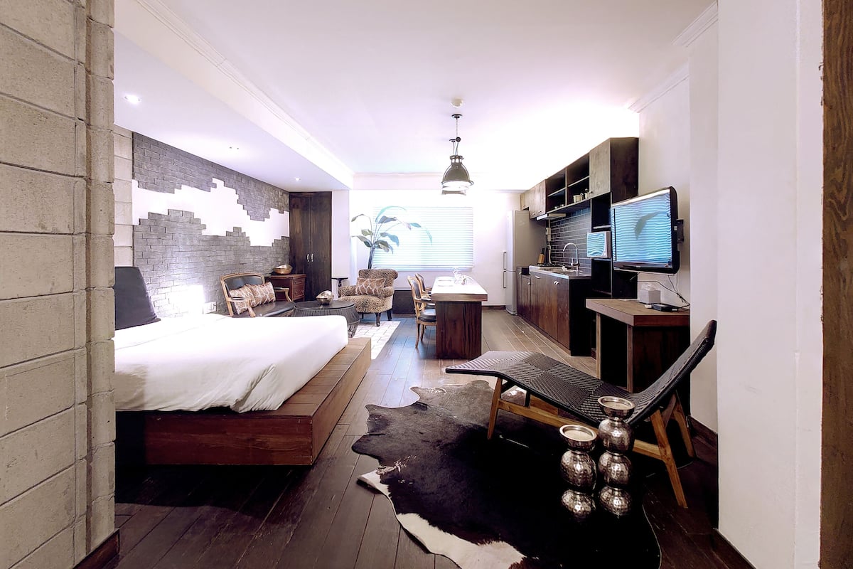Un dormitorio moderno con una cama, un escritorio, una silla y un televisor.