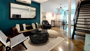 Ein modernes Wohnzimmer mit einer Couch, Sesseln, einem Couchtisch und einer Treppe.