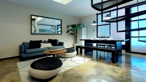 Ein modernes Wohnzimmer mit einer Couch, Hocker, einem Couchtisch und einem Essbereich mit einer Bank und Tisch.