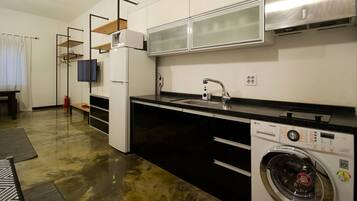 A compact kitchen with a washing machine, a microwave, and a sink.
