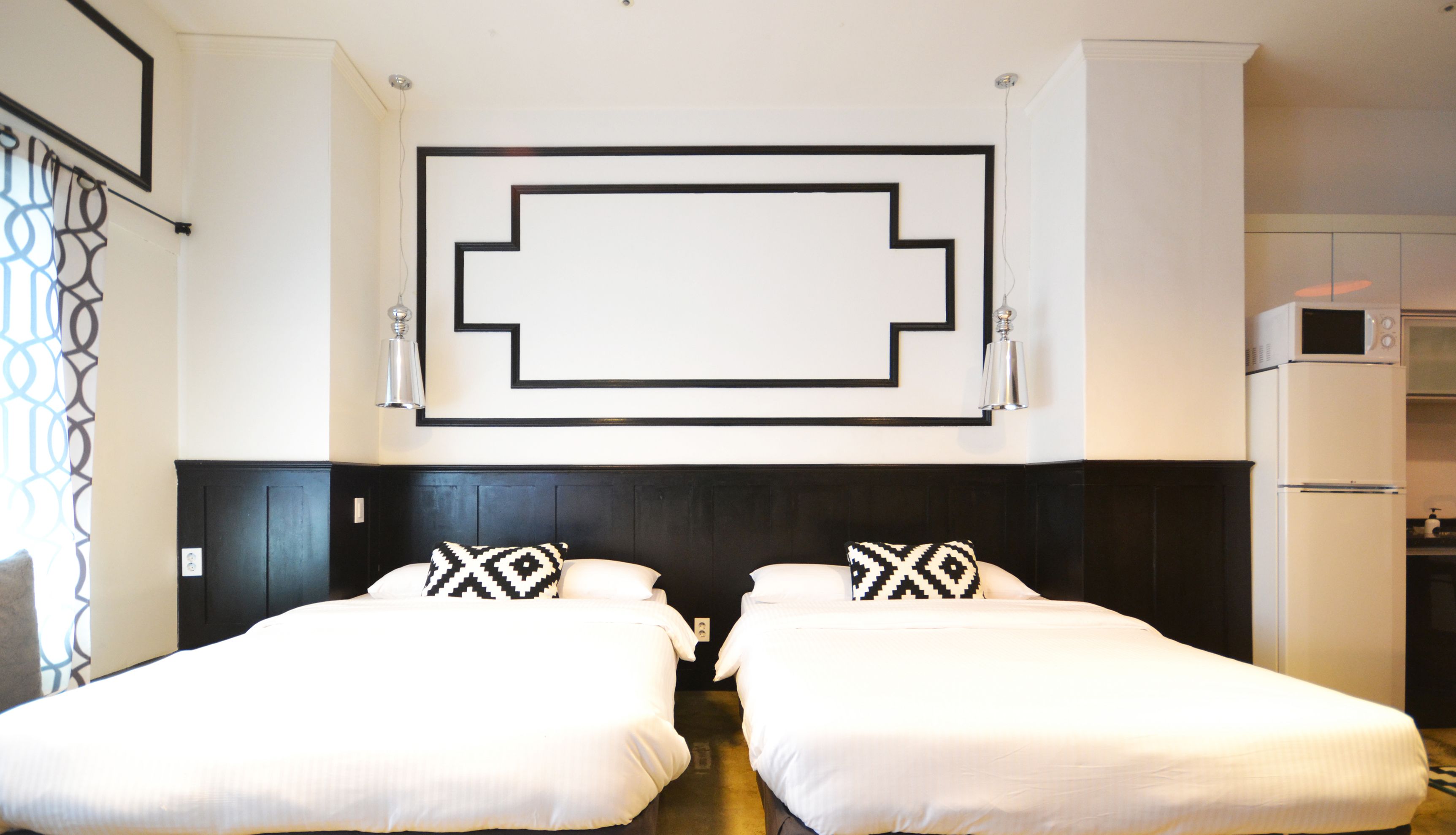 A hotel room with two beds, a large wall decoration, a microwave, and a refrigerator.
