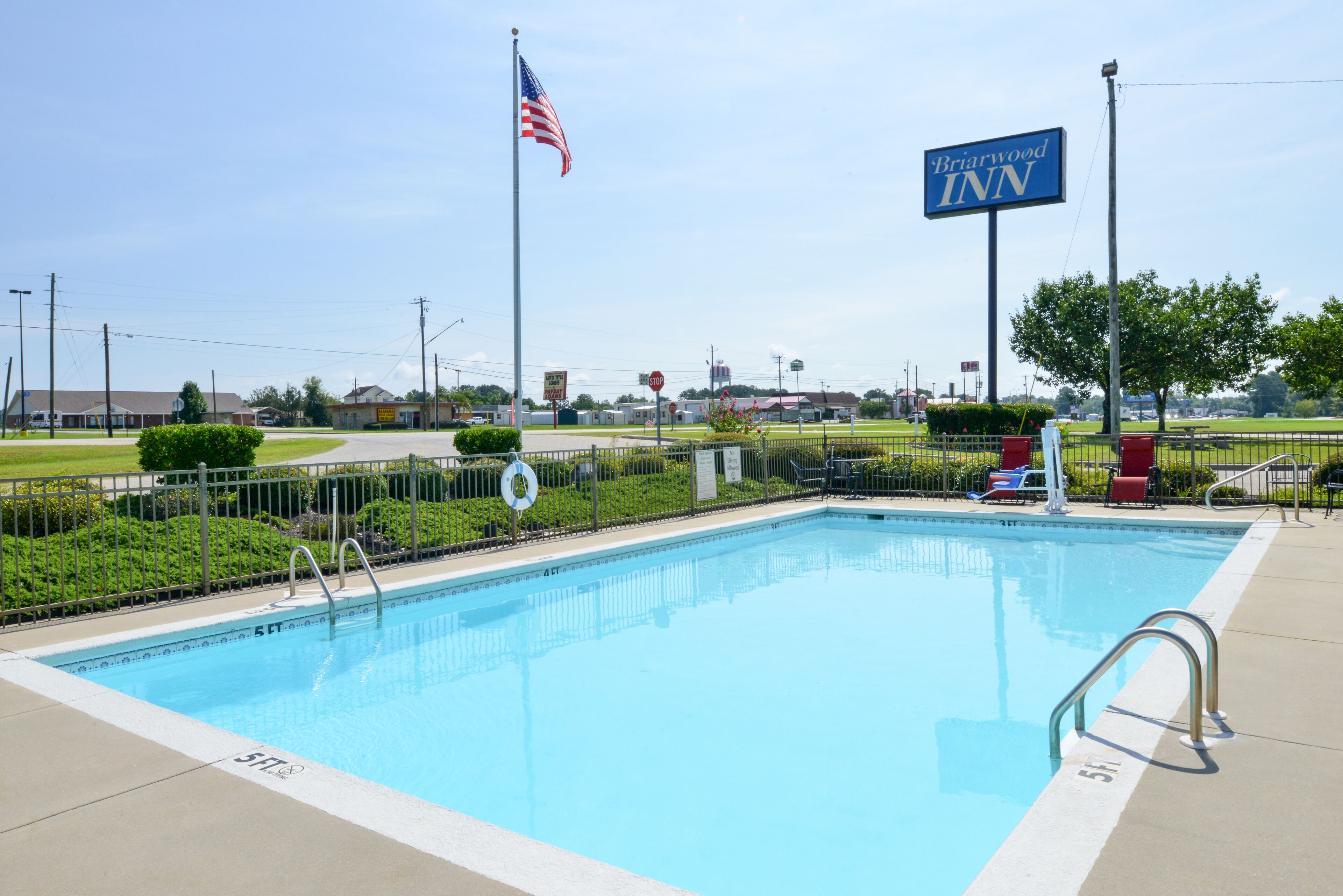 A swimming pool with a lifeguard stand, a flag, and a sign for Briarwood Inn.