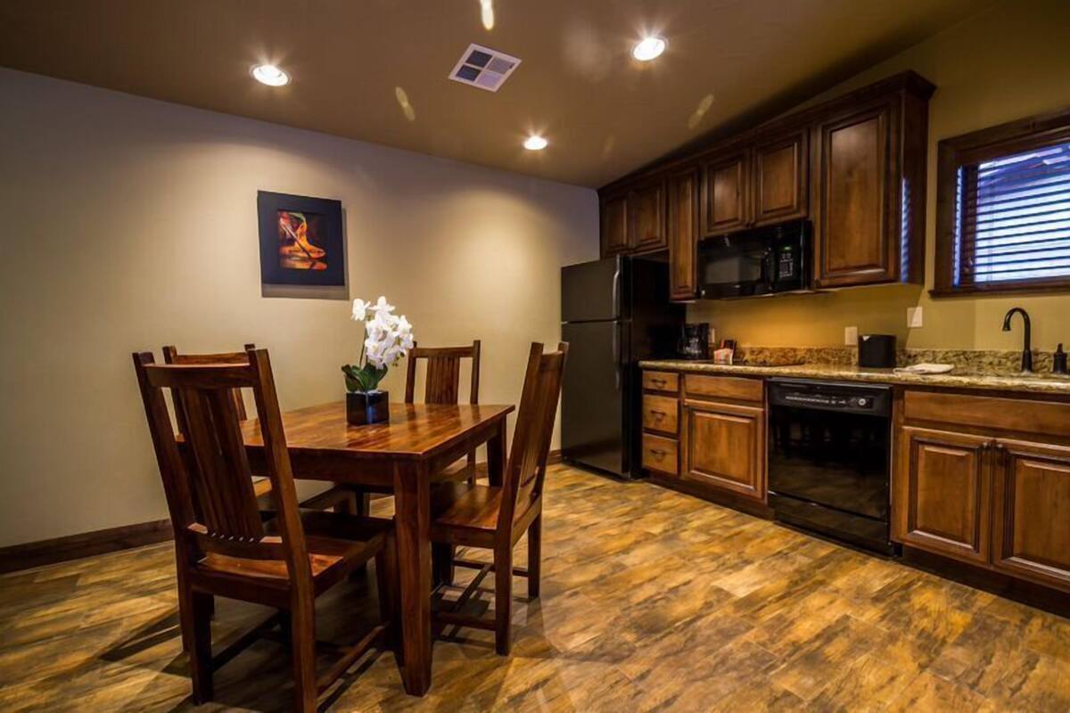 A kitchen with wooden cabinets, a dining table with chairs, and a refrigerator.