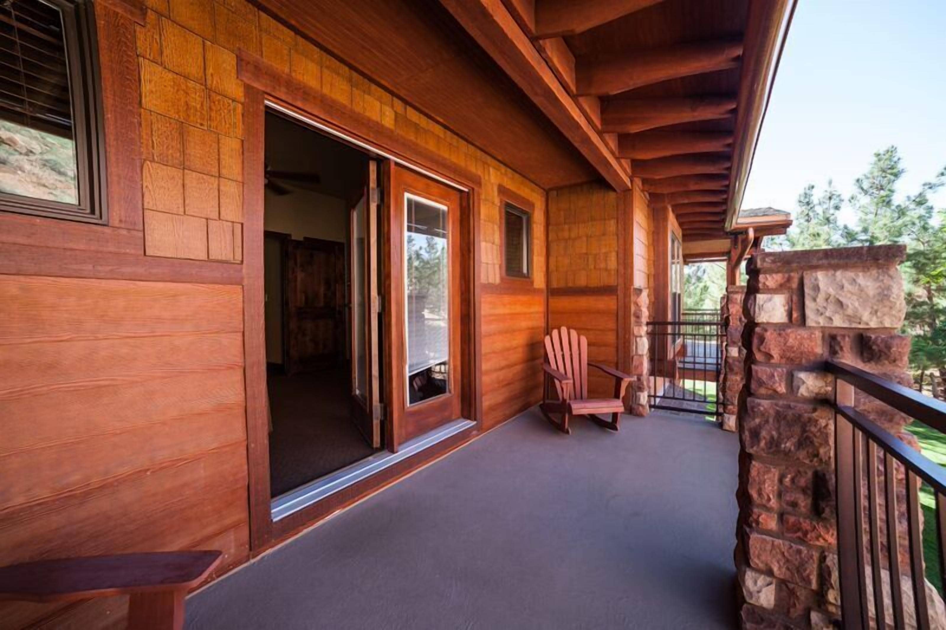 A wooden exterior with a covered porch, a sliding glass door, and a stone wall.