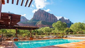 A swimming pool with a mountain view, lounge chairs, and a pergola. - Cable Mountain Lodge (Springdale)