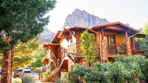 A rustic lodge with a stone facade, wooden balconies, and a staircase leading to the entrance. - Cable Mountain Lodge (Springdale)