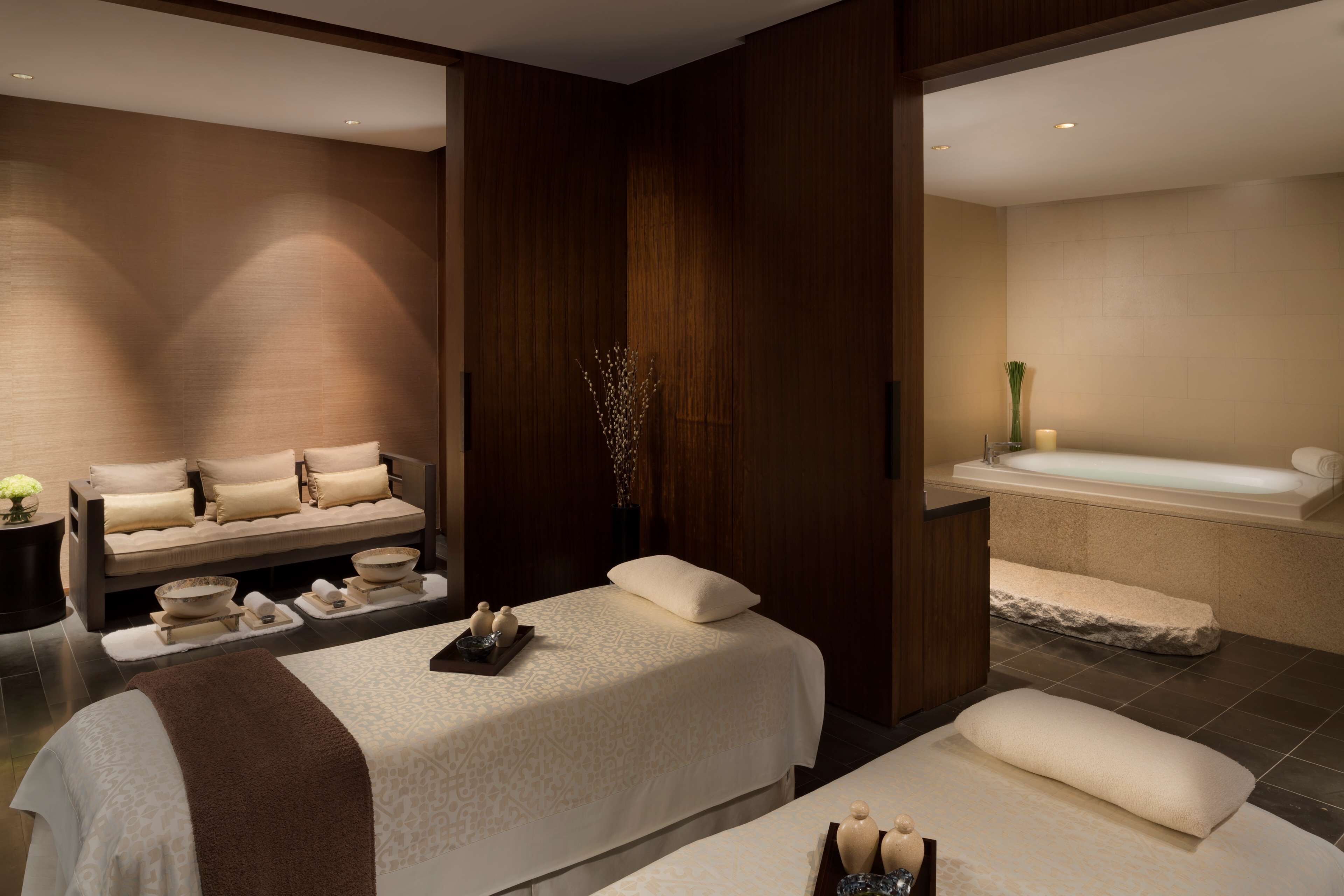 A modern spa room with a massage area, a bathtub, and a reception desk.