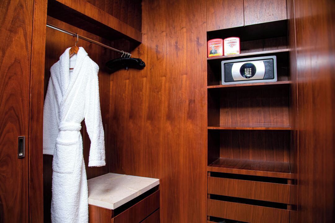 Un vestidor de madera con bata colgada, un microondas y estantes de almacenamiento.