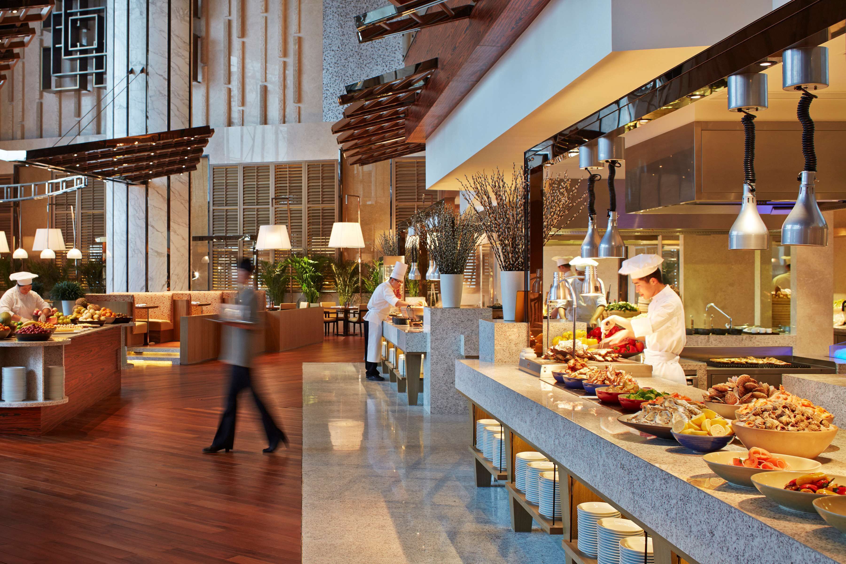 Un hall d’hôtel moderne, doté d’un aménagement spacieux, d’un comptoir d’accueil central et d’un buffet proposant une variété de plats.