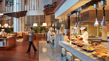 Un hall d’hôtel moderne, doté d’un aménagement spacieux, d’un comptoir d’accueil central et d’un buffet proposant une variété de plats.