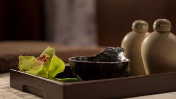 A tray with a green orchid, a black bowl, and two ceramic salt shakers on a textured surface.
