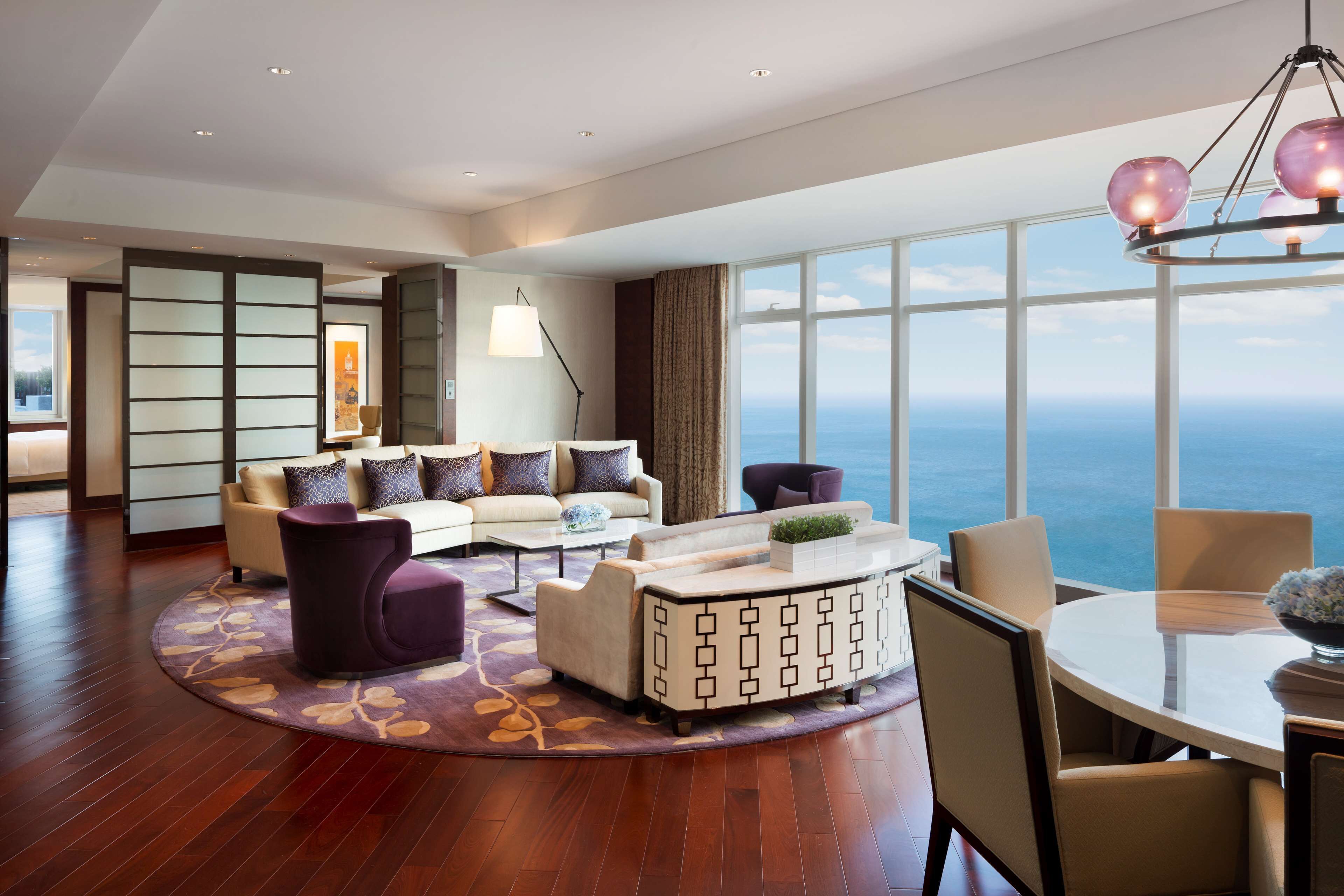 A modern living room with a sofa, armchairs, a coffee table, and a dining area with chairs and a table.