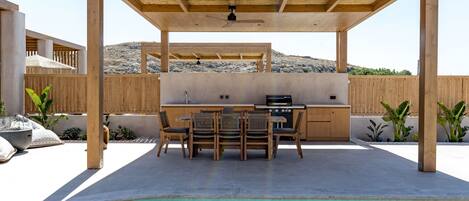 A poolside area with a wooden pergola, a bar, and a seating arrangement.