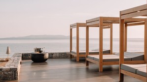 A beachside terrace with wooden beds and a fire pit, overlooking the sea. - Unique Blue! Resort and Villas Adults Only (Hersonissos)