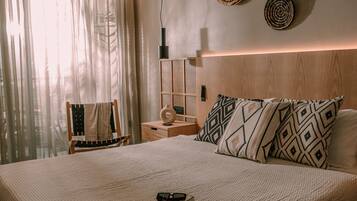 Un dormitorio con una cama grande, un ventilador de techo, una mesita de noche con lámpara y vistas a un balcón con cortinas.