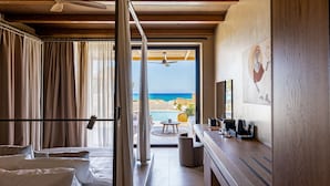 A hotel room with a bed, a desk with a coffee maker, and a view of the beach. - Unique Blue! Resort and Villas Adults Only (Hersonissos)