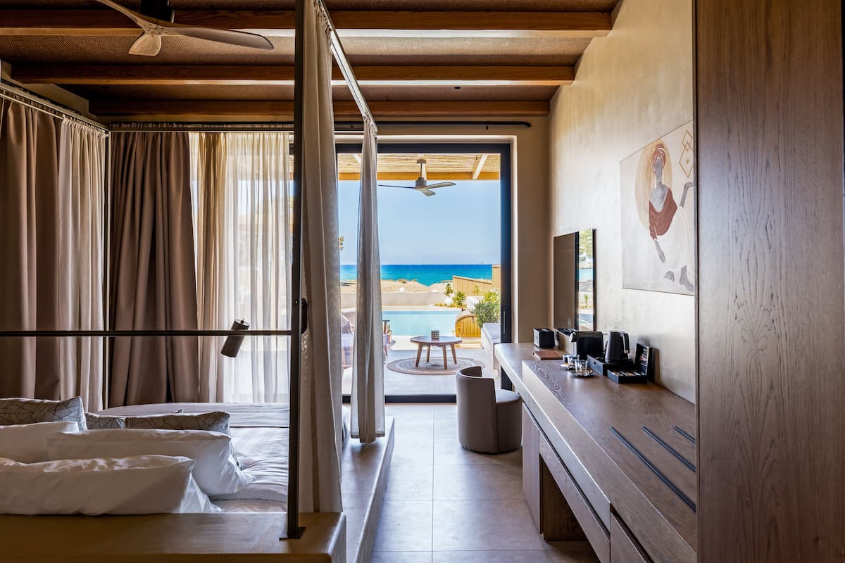 Ein Hotelzimmer mit Bett, Schreibtisch mit Kaffeemaschine und Blick auf den Strand.