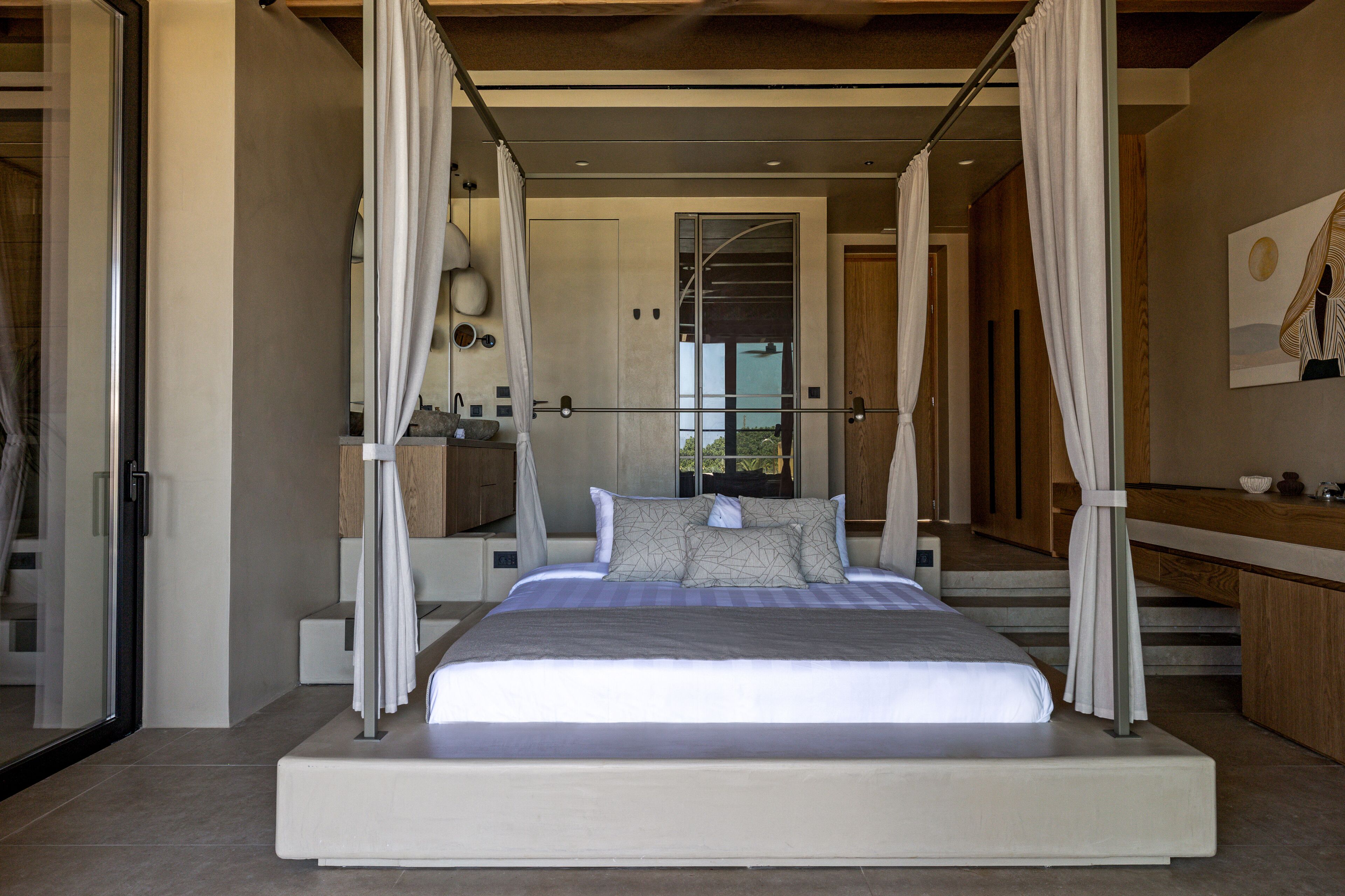 A modern bedroom with a large bed, a canopy, and a view of the outdoors.
