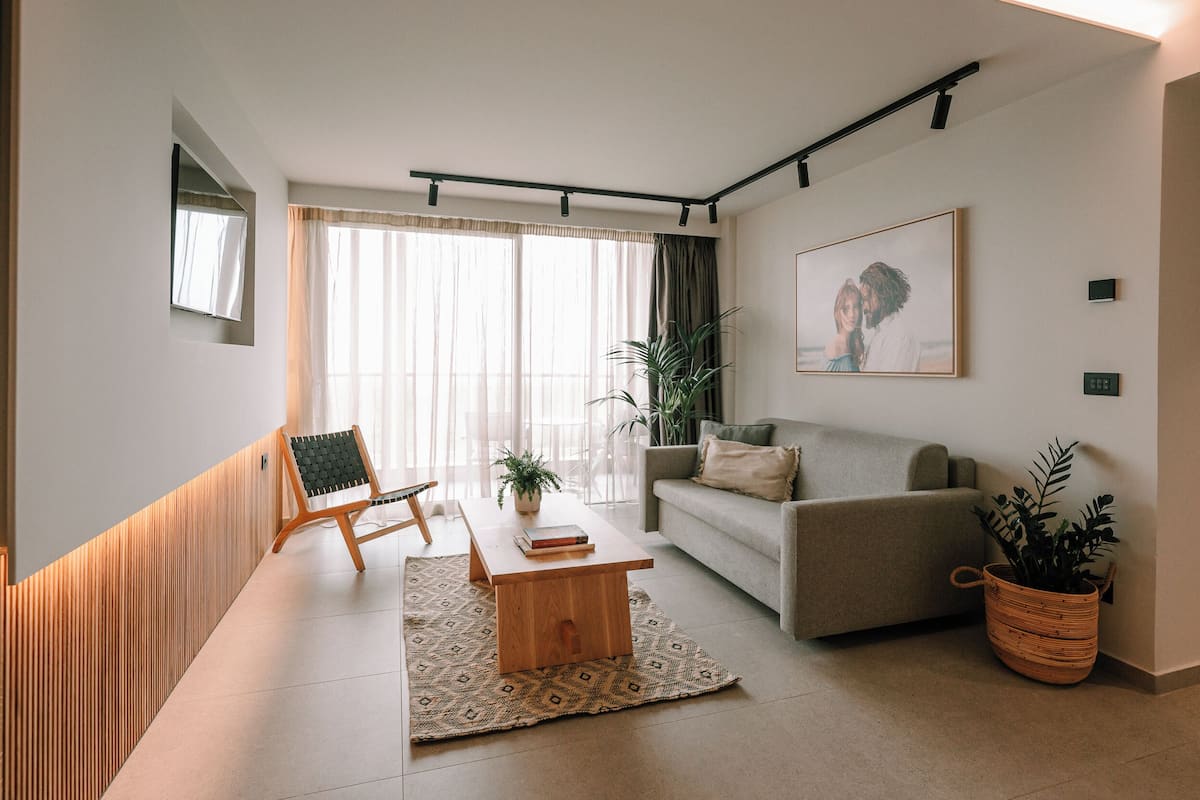 Ein modernes Wohnzimmer mit Sofa, Couchtisch, Sessel und Zimmerpflanze.
