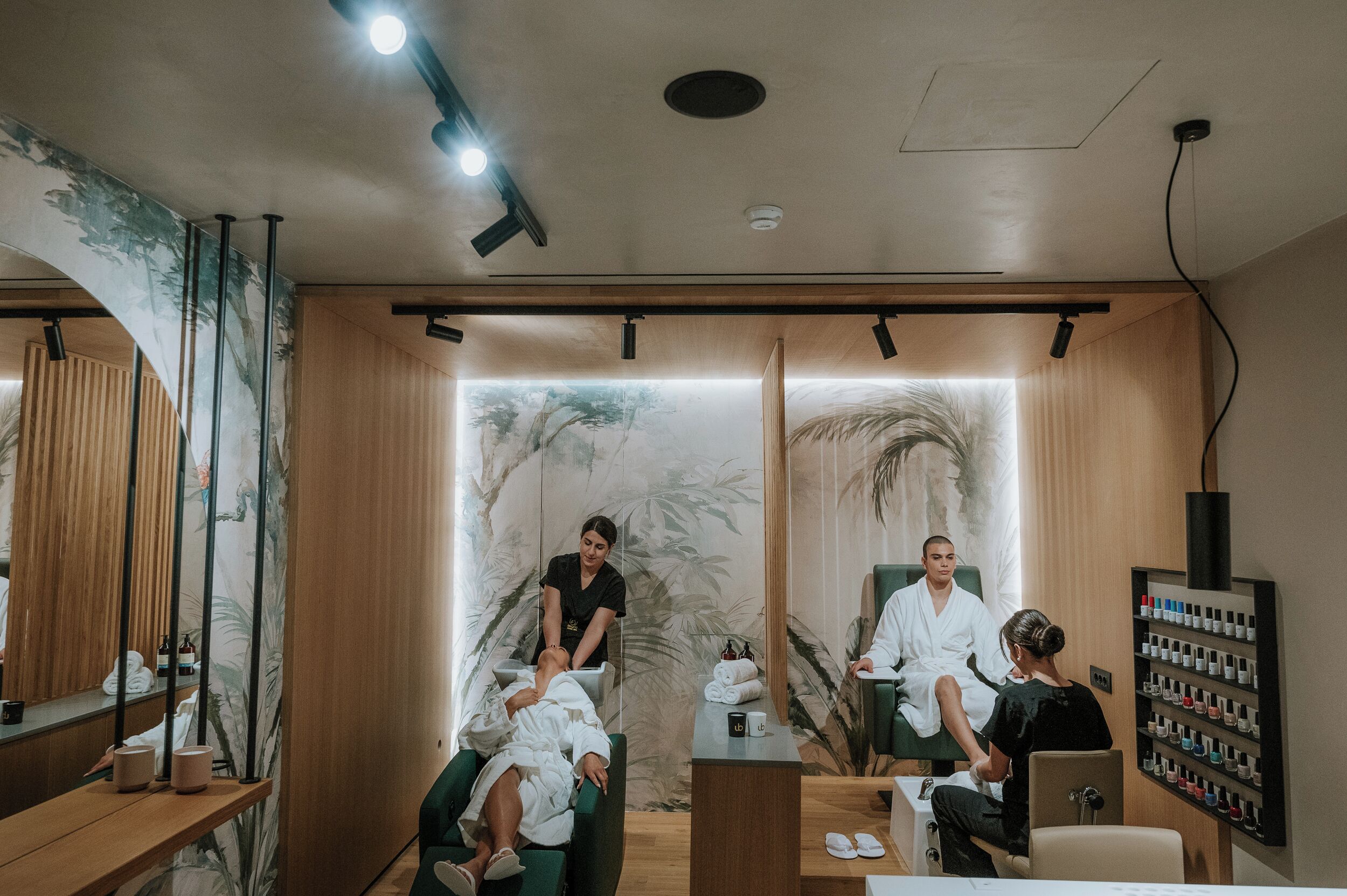 A spa room with a massage chair, a treatment table, and a wall-mounted shelf with bottles.