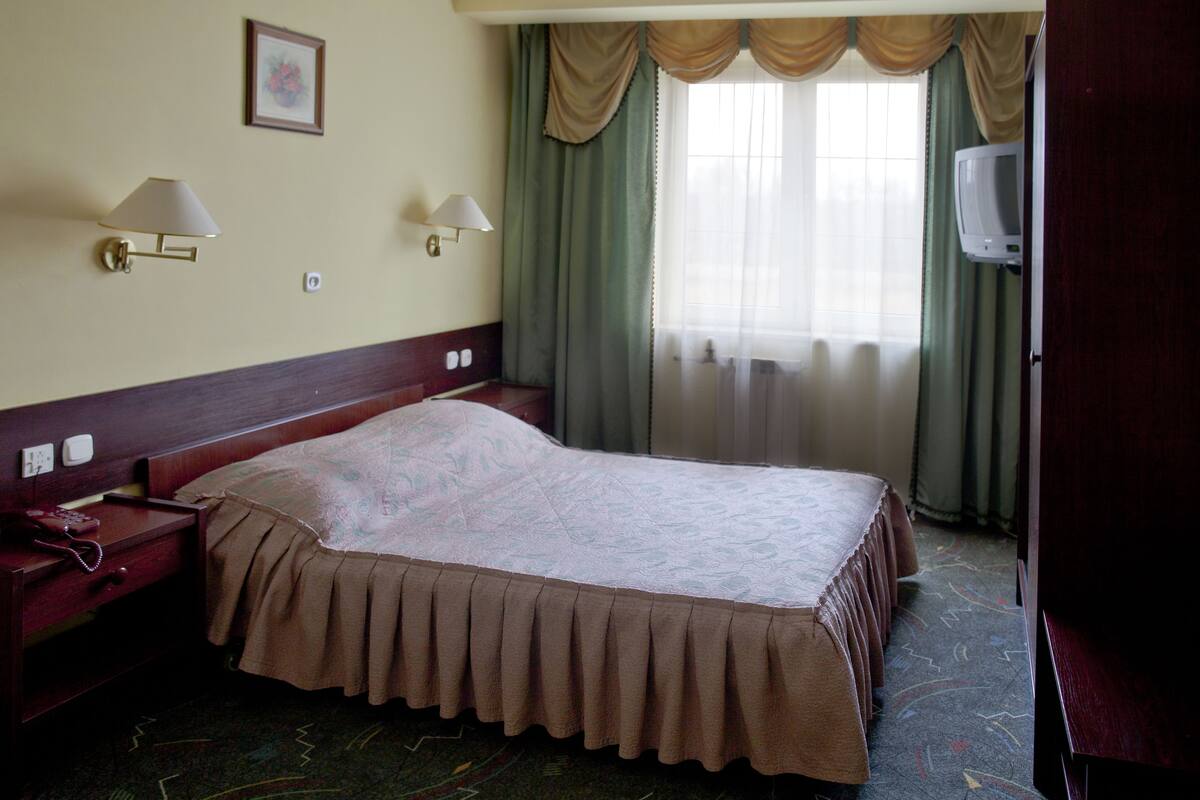 أغطية فراش متميزة وخزنة داخل الغرفة ومكتب وستائر تعتيم