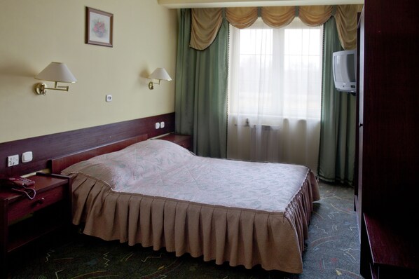 أغطية فراش متميزة وخزنة داخل الغرفة ومكتب وستائر تعتيم