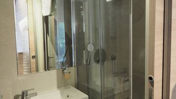 Un baño moderno con ducha de vidrio, lavamanos con espejo y muebles de madera.
