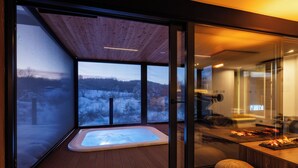 A modern spa area with a hot tub, wooden deck, and glass doors offering a view of a snowy landscape. - Plitvice Holiday Resort - Campsite (Rakovica)