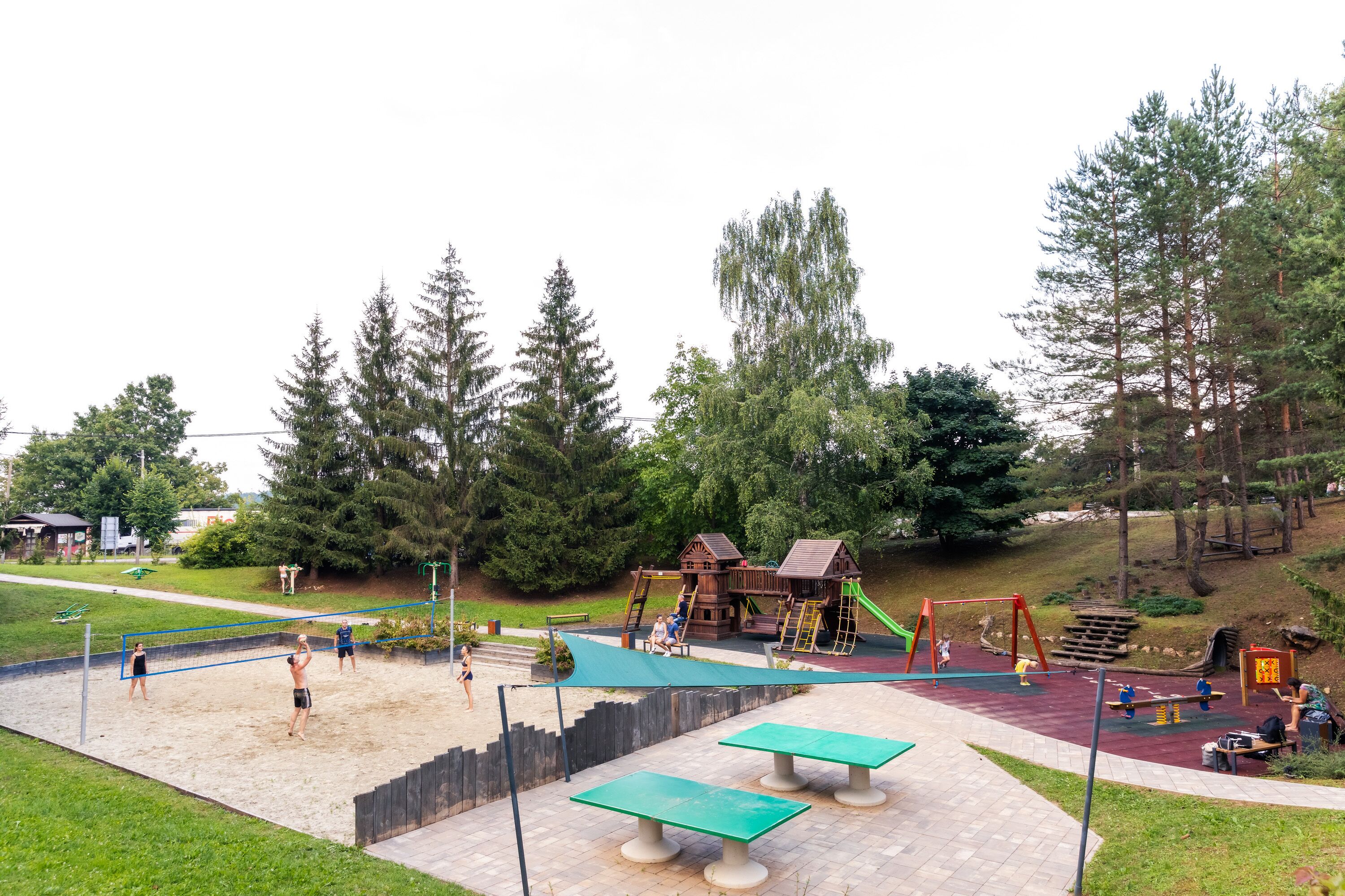 A playground with sand volleyball courts, swings, and climbing structures.