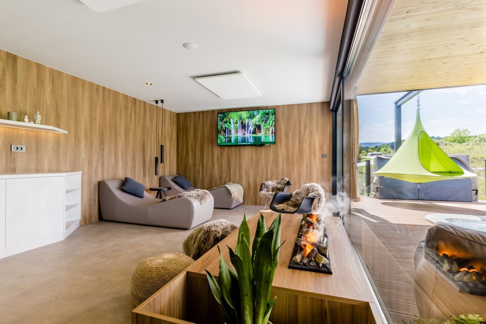 A modern living room with a fireplace, comfortable seating, a TV, and a view of the outdoors.