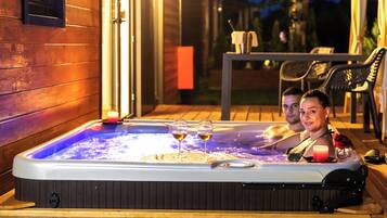 Un bain à remous où se trouvent deux personnes et deux verres de vin.