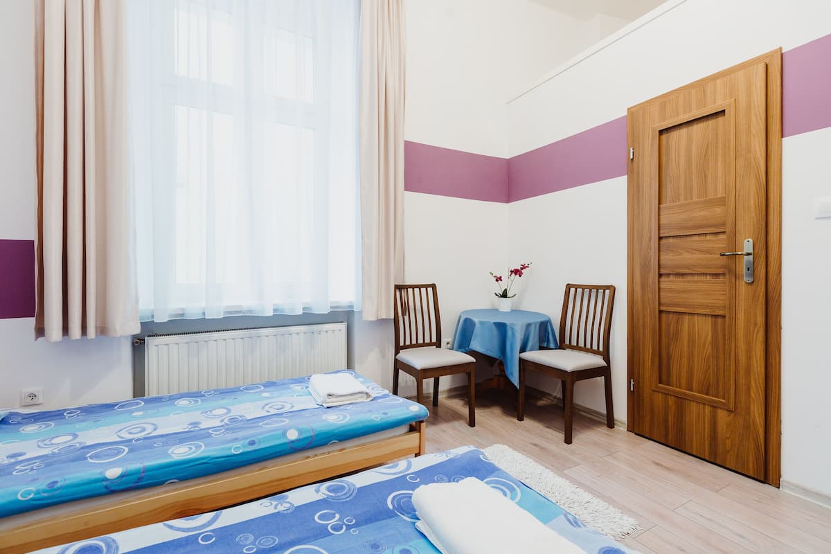 Ein Schlafzimmer mit einem Bett, einem Tisch mit Stühlen, einer Holztür und einem Fenster mit Vorhängen.
