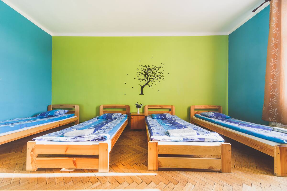 Ein Zimmer mit drei Holzbetten, einer grünen Wand und einer Baumaufkleber.