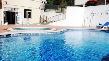 Een buitenzwembad, parasols voor strand/zwembad