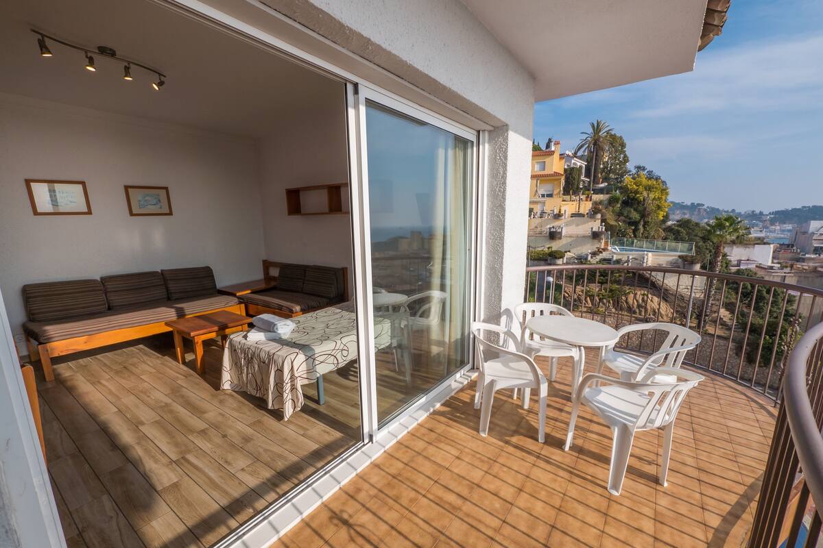 A balcony with a wooden floor, a sofa, a table, and two chairs.