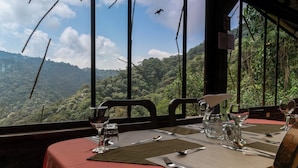 Mesa preparada para comer con vista a una cadena montañosa boscosa.