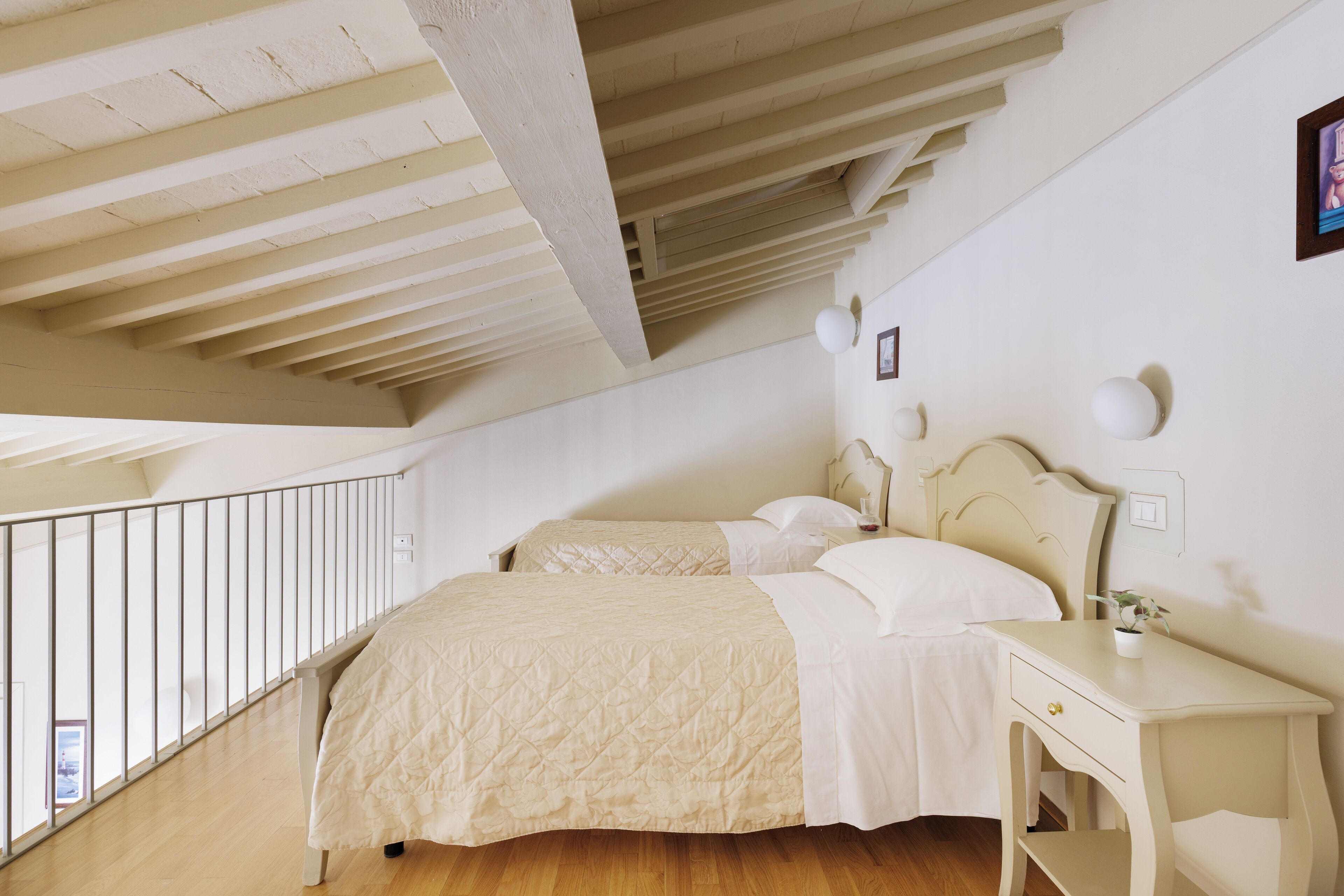 Une chambre avec deux lits, un plancher en bois, un balcon et un plafond blanc.
